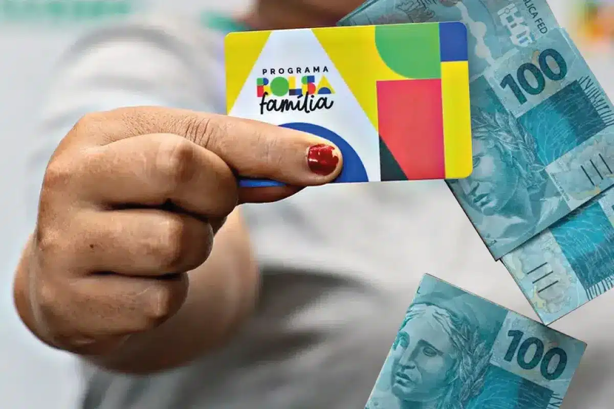 Bolsa Família de março - Pagamentos e cidades monitoradas Cartão do Programa Bolsa Família sendo exibido junto a cédulas de R$100, ilustrando o pagamento das parcelas de março para as famílias beneficiadas.