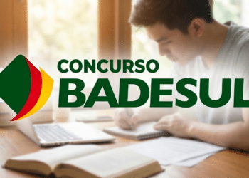 Homem faz anotações em caderno ao lado de livros e notebook com logo do BADESUL