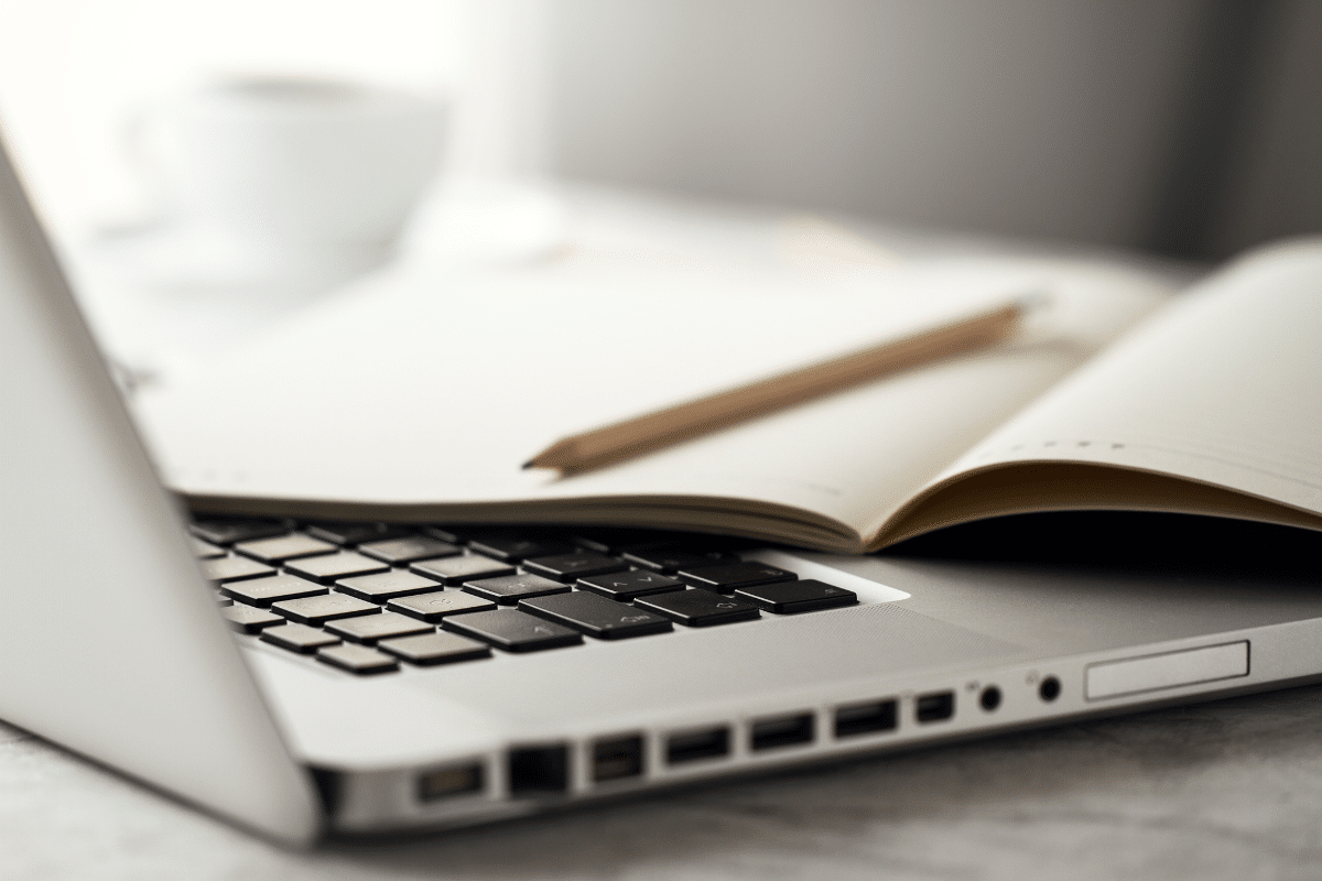 Notebook com caderno aberto e lápis sobre o teclado em mesa clara