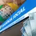 Notas de 100 reais e a fachada do INSS, representando o pagamento do benefício de março de 2026 e a dúvida sobre o pagamento da parcela do 13º salário junto.