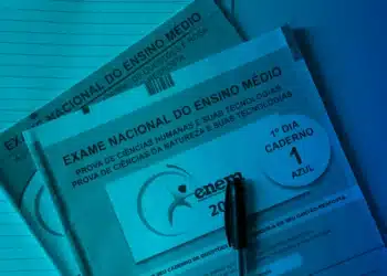 Foto dos cadernos de prova do Enem sobre uma mesa, representando temas atuais que podem aparecer no exame de 2026.