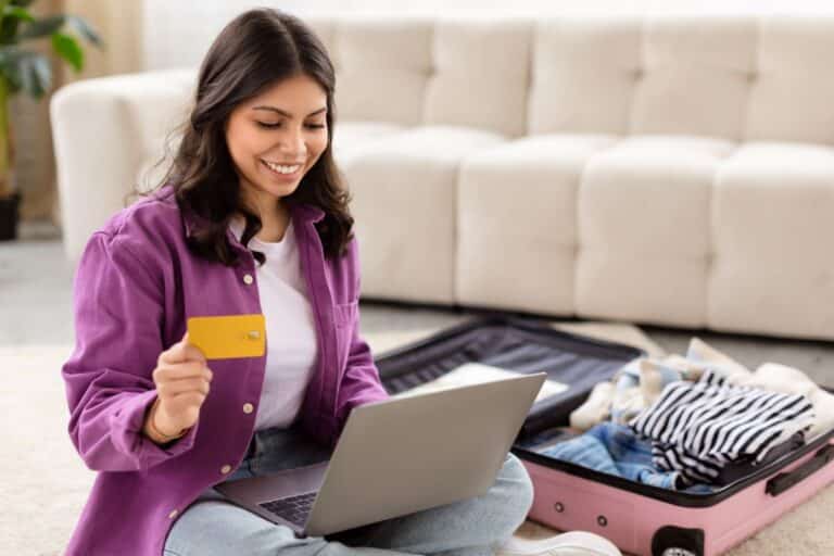 Mulher sorrindo enquanto planeja sua viagem usando um laptop e segurando um cartão de crédito, destacando a facilidade da busca por passagens aéreas com ferramentas como o Skyscanner integrado ao ChatGPT.