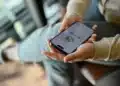 Pessoa segurando smartphone com WhatsApp aberto, ilustrando como evitar mensagens de listas de transmissão.