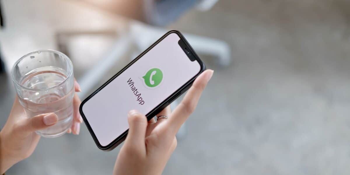 Pessoa segurando smartphone com tela inicial do WhatsApp exibida, ilustrando mudanças de personalização no aplicativo.