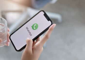 Pessoa segurando smartphone com tela inicial do WhatsApp exibida, ilustrando mudanças de personalização no aplicativo.