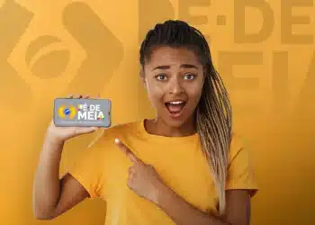 Pessoa mostrando celular destacando a tela com o logo Pé-de-Meia e título sobre poupança escolar, representando o acesso à conta do benefício