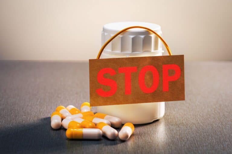 Medicamentos e cápsulas com placa de “stop”, representando proibição de produtos irregulares pela Anvisa.