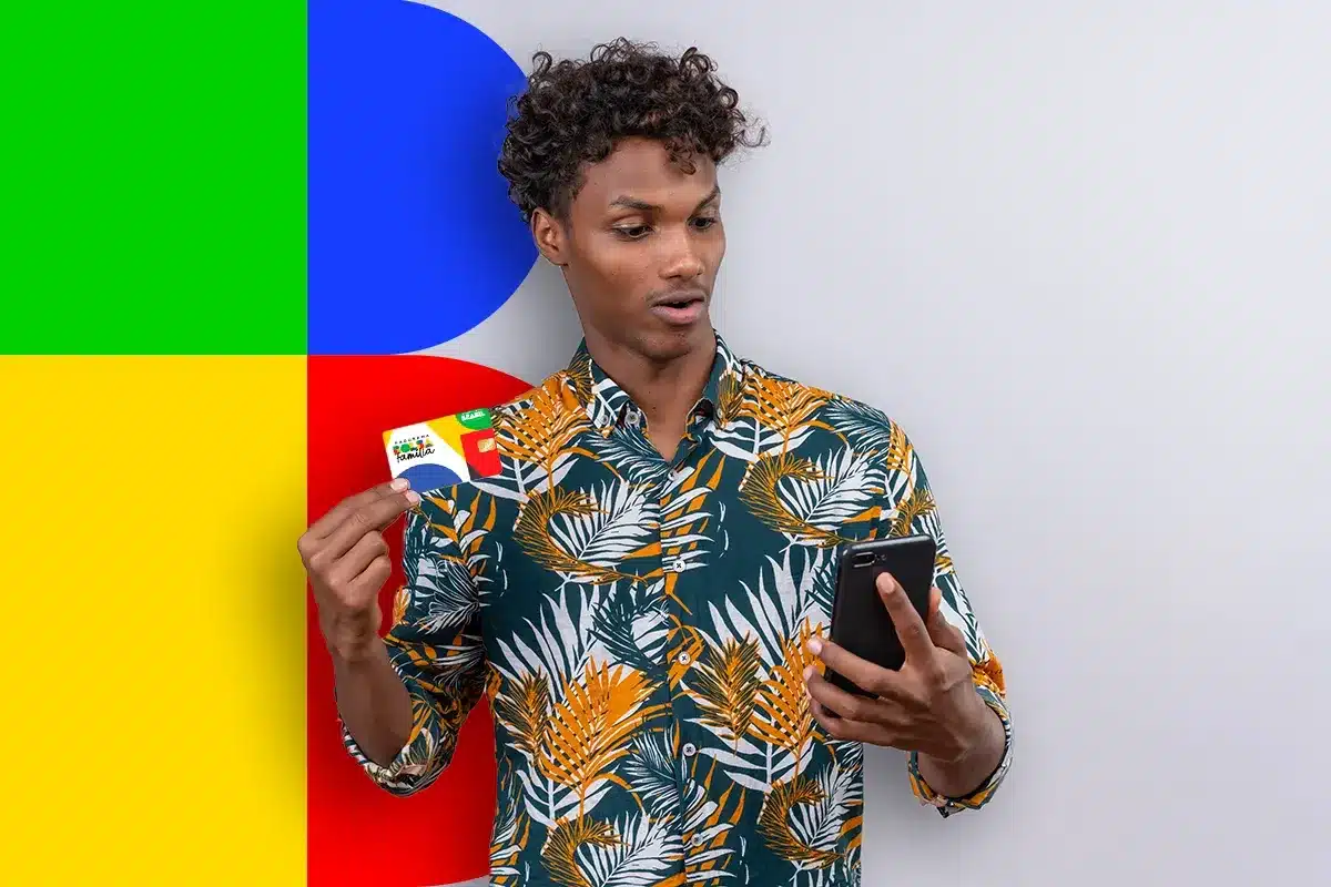 Homem segurando cartão do Bolsa Família enquanto verifica informações no celular sobre atualização cadastral
