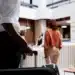 Hóspede chegando à recepção de hotel com mala para realizar check-in digital obrigatório