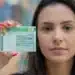 Mulher segurando sua carteira de motorista brasileira, destacando o documento em primeiro plano.
