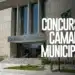 Prédio moderno da Câmara Municipal com fachada em concreto, escadaria central e bandeira do Brasil hasteada