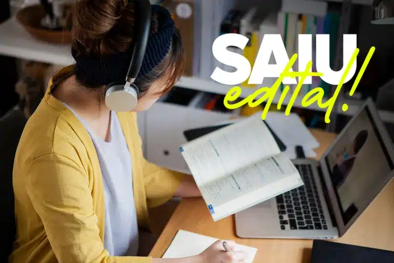 Jovem estudando com fone de ouvido e livro aberto ao lado de notebook com texto Saiu Edital em destaque representando concurso da Prefeitura de Caibaté (RS)