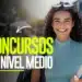 Mulher jovem de cabelos cacheados e blusa verde segura livros, sorrindo, com texto "Concursos de Nível Médio"