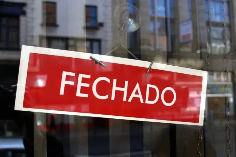 Placa de “fechado” em vitrine indicando funcionamento suspenso no feriado de 1º de maio