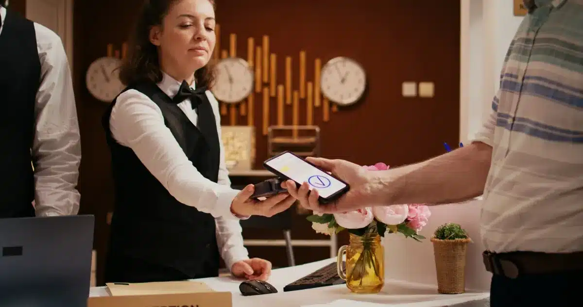 Recepcionista de hotel realizando check-in digital com hóspede via smartphone na FNRH digital