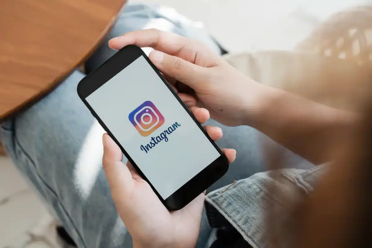 Pessoa segurando smartphone com o logo do Instagram na tela, ilustrando o lançamento do 'Instants'.