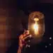 Mão alcançando lâmpada acesa, simbolizando o alerta sobre golpes digitais no programa Luz do Povo.