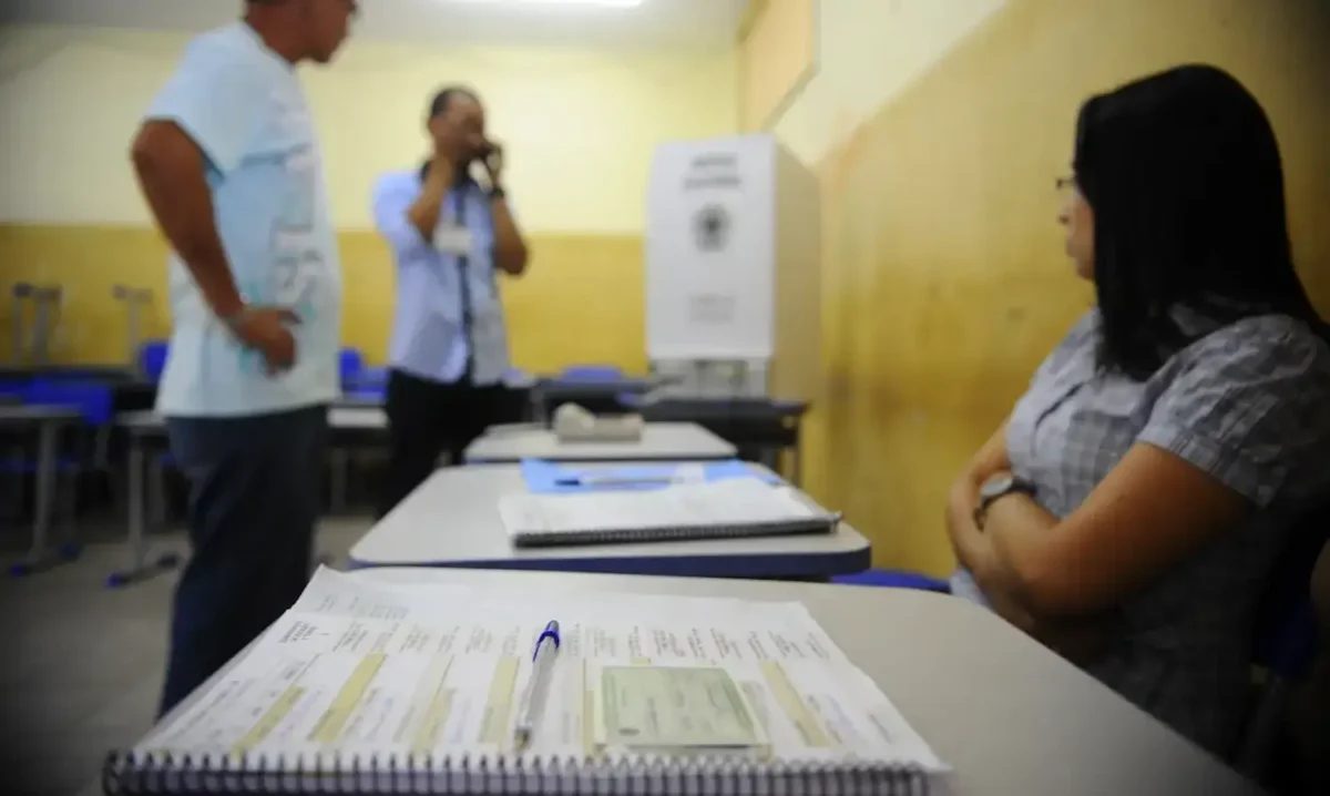 Mesária aguardando enquanto eleitores estão registrando seus votos nas Eleições.