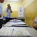 Mesária aguardando enquanto eleitores estão registrando seus votos nas Eleições.