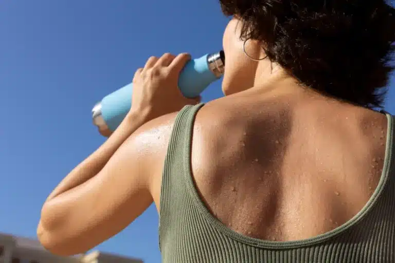 Mulher suando enquanto bebe água representando onda de calor intensa que afeta estados brasileiros