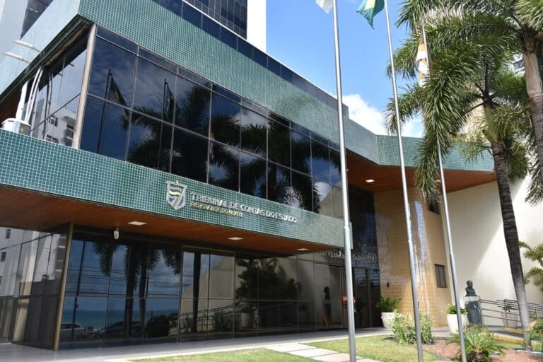 Concurso TCE RN 2026 - fachada do Tribunal de Contas do Estado do Rio Grande do Norte com bandeiras e palmeiras