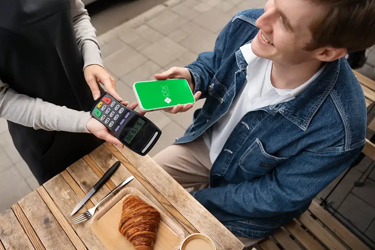 Turista pagando café com Pix em maquininha de cartão no exterior.