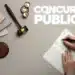 mesa com martelo de juiz e caderno aberto, Nome "CONCURSOS PÚBLICOS" em destaque.