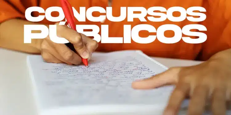 Candidato escrevendo em papel com caneta laranja e nome "CONCURSOS PÚBLICOS" destacado.