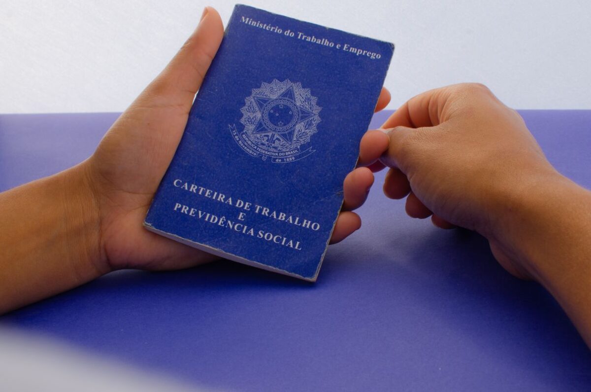 Carteira de Trabalho física do Brasil em mãos de trabalhador.