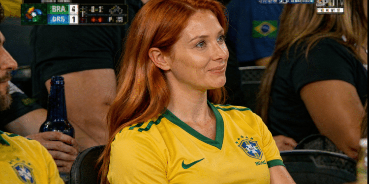 Mulher sorrindo sentada em arquibancada de jogo de futebol.