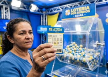 Mulher segura bilhete da Loteria dos Sonhos Ceará com dezenas marcadas, ao fundo globo de sorteio com bolas azuis e amarelas