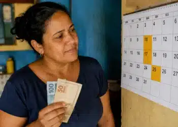 Beneficiária do Bolsa Família segura dinheiro e observa calendário com datas, representando os pagamentos de junho.