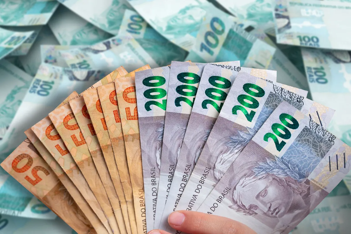 Mão segurando cédulas de reais, simbolizando o pagamento do salário dentro do prazo do 5º dia útil de maio.