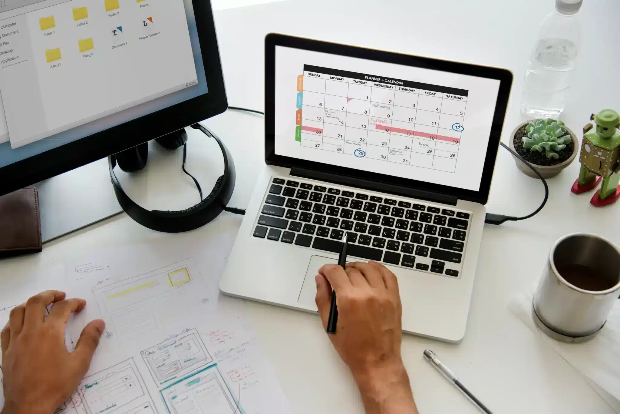 Profissional marca datas em planner exibido no notebook, representando o planejamento de pontos facultativos e feriados em 2026