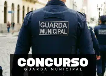 Guardas Municipais de uniforme azul marinho patrulham rua de paralelepípedos em centro histórico brasileiro