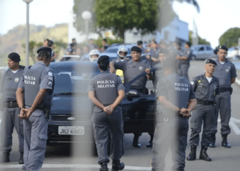 Policiais militares uniformizados em formação ao lado de viaturas durante operação ao ar livre