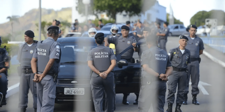 Policiais militares uniformizados em formação ao lado de viaturas durante operação ao ar livre