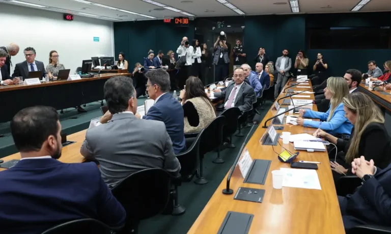 Parlamentares reunidos em torno de mesa durante sessão de comissão na Câmara dos Deputados.