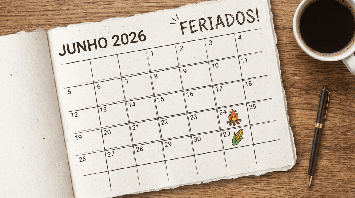 Calendário de junho 2026 sobre mesa de madeira com fogueira no dia 24 e milho no dia 29, xícara de café e caneta.