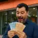 Trabalhador segurando notas de real em frente a banco, representando a liberação do saque-aniversário do FGTS em 2026.