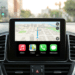 Painel de carro exibindo Apple CarPlay com mapa 3D de navegação e ícones de Music, Maps, Phone e Mensagens.