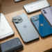 Seis iPhones de diferentes gerações, do SE ao 13 Pro, expostos sobre mesa de madeira clara.