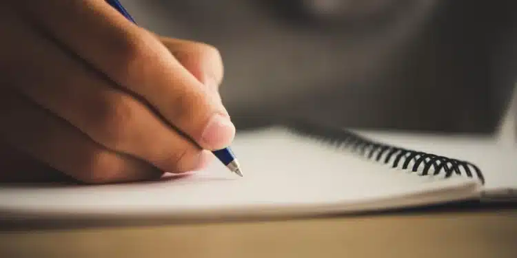 Professor escrevendo anotações em caderno representando a atividade de aperfeiçoamento em matemática