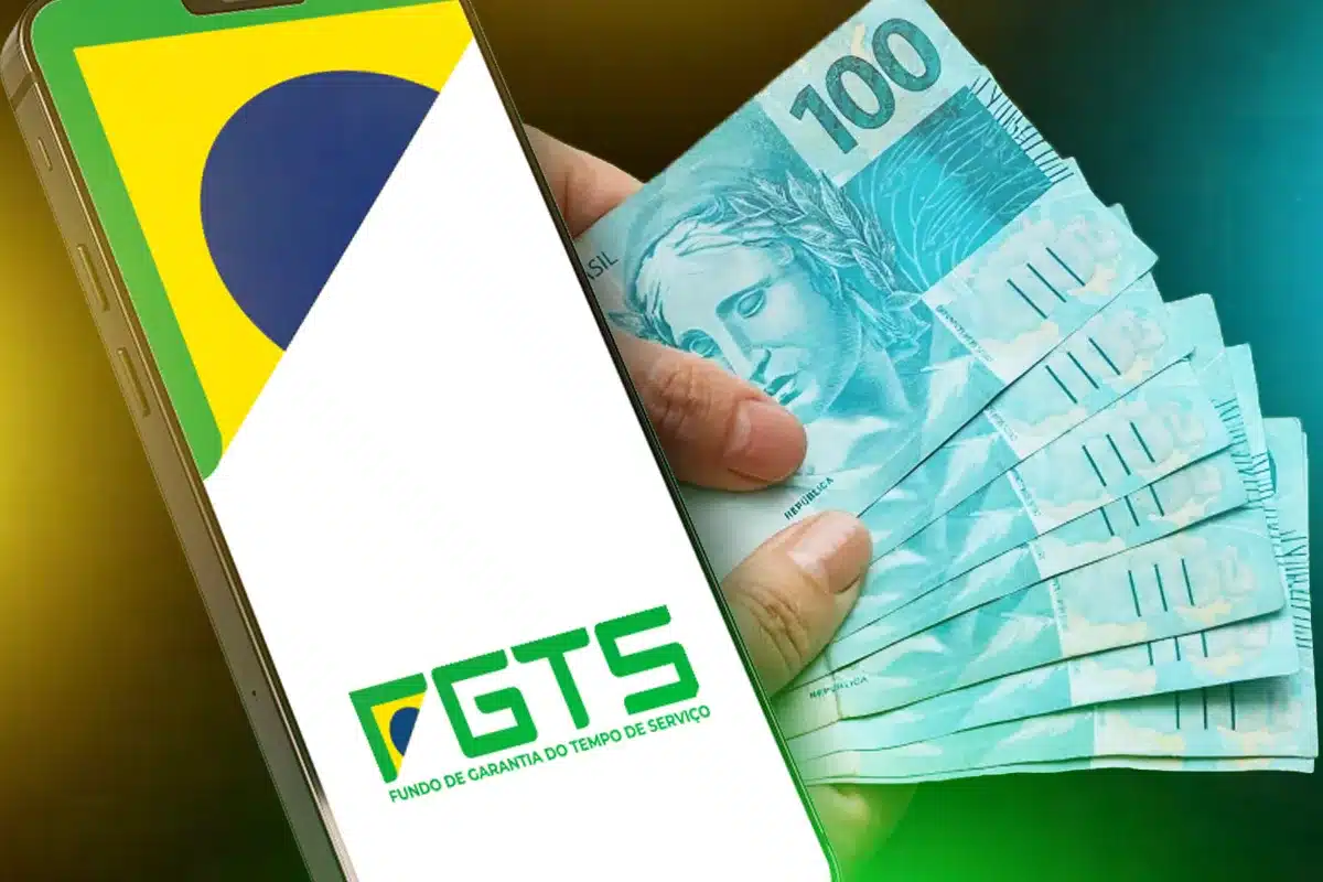 Celular exibe a logomarca do FGTS enquanto uma mão segura várias notas de cem reais ao lado.