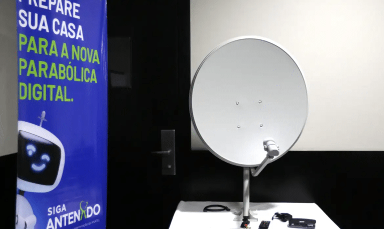 Kit da nova parabólica digital exposto ao lado do banner da campanha Siga Antenado da Anatel sobre a troca de antenas
