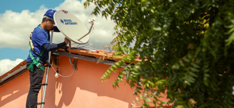 Técnico instala antena parabólica digital Brasil Antenado no telhado de casa residencial