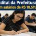 Candidatos sentados em sala realizando prova de concurso público, jovem de óculos e camiseta listrada em destaque.