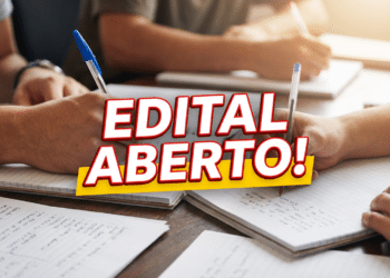 Mãos de estudantes escrevendo em cadernos sobre mesa de madeira com texto "Edital Aberto!" em vermelho e amarelo.