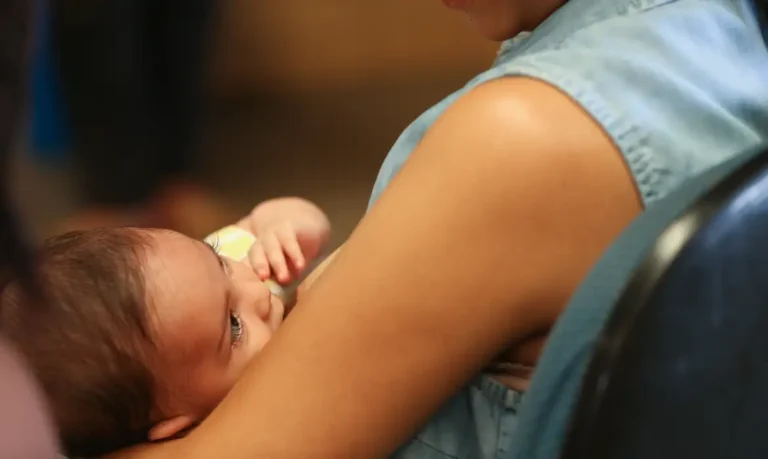 Mãe segura bebê recém-nascido no colo, representando o desafio de conciliar a maternidade com a vida profissional