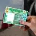 Pessoa segurando uma CNH em frente a um veículo, representando regras de renovação automática da carteira de motorista.
